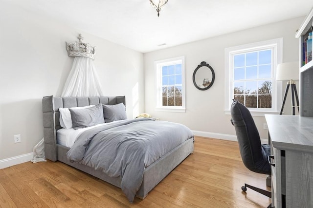 bedroom featuring light wood-type flooring, multiple windows, and baseboards