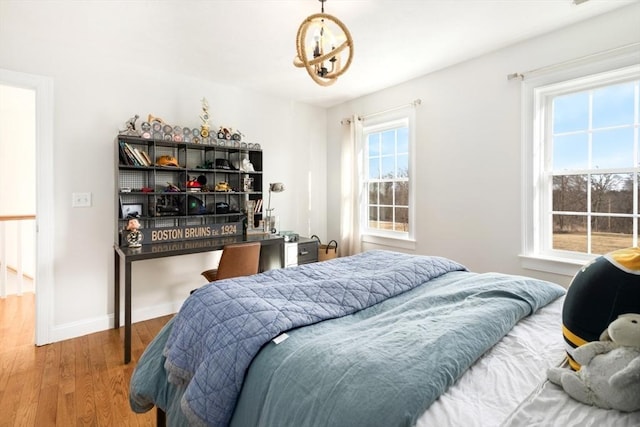 bedroom with an inviting chandelier, baseboards, and wood finished floors