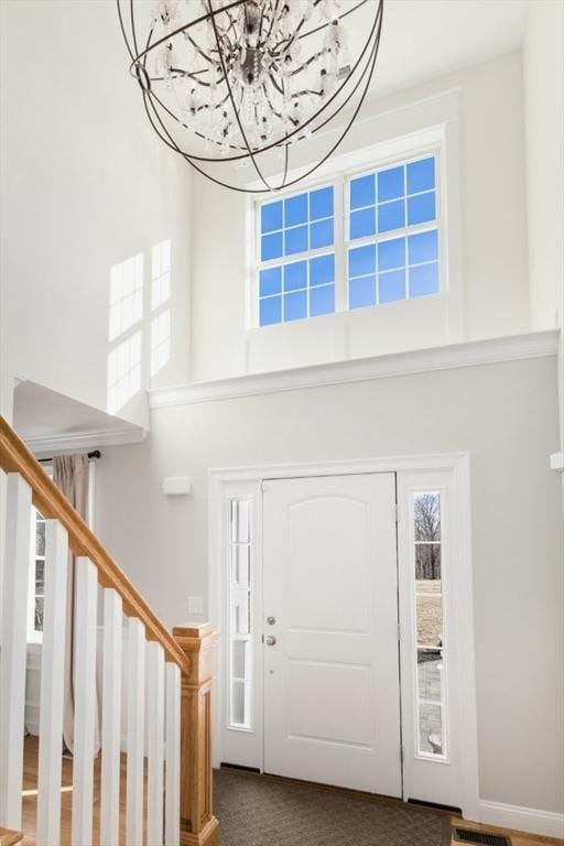 entrance foyer featuring visible vents, stairs, and a towering ceiling