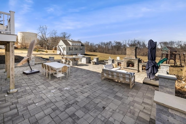 view of patio / terrace featuring outdoor dining area, an outdoor stone fireplace, and an outdoor structure