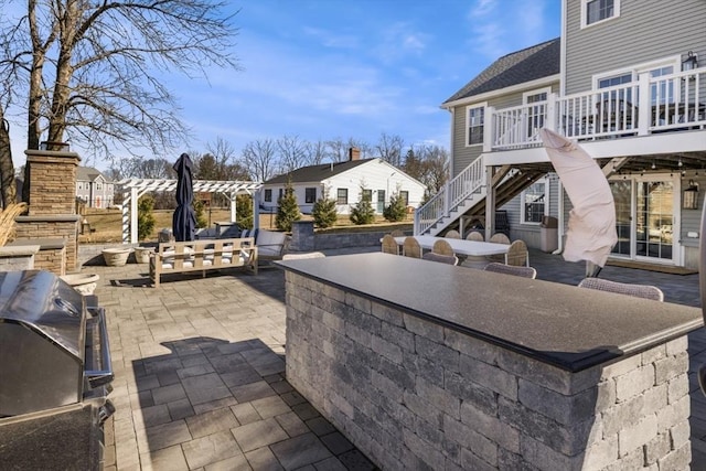 view of patio with a residential view, stairs, a stone fireplace, outdoor dining area, and a deck