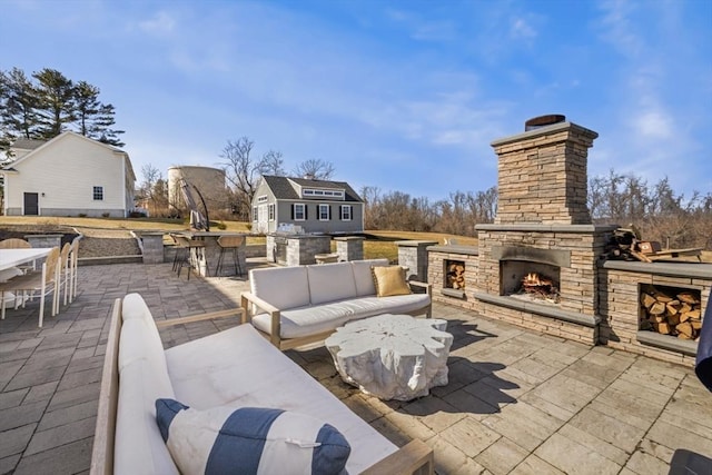 view of patio featuring outdoor dining space, an outdoor structure, an outdoor living space with a fireplace, and outdoor dry bar