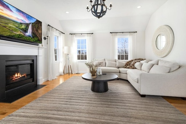 living area with a glass covered fireplace, recessed lighting, lofted ceiling, and wood finished floors