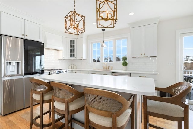 kitchen featuring custom range hood, a healthy amount of sunlight, appliances with stainless steel finishes, and a sink