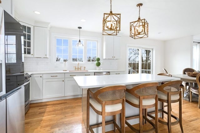 kitchen with a wealth of natural light, light wood finished floors, appliances with stainless steel finishes, and a sink