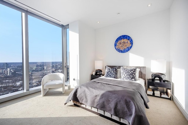 bedroom featuring multiple windows, light carpet, and a wall of windows