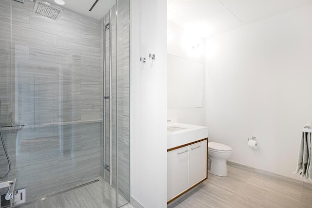 bathroom featuring vanity, a shower with shower door, and toilet