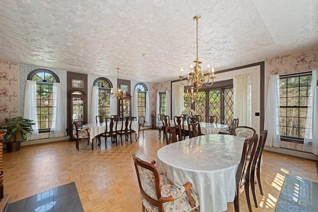 dining room featuring an inviting chandelier, a textured ceiling, baseboards, and wallpapered walls