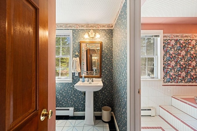 bathroom with tile patterned flooring, baseboard heating, wallpapered walls, a baseboard radiator, and tiled bath