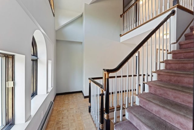 stairs with baseboards and a towering ceiling
