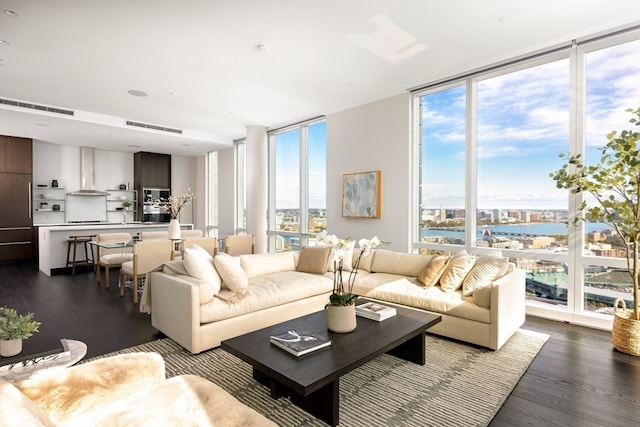 living room with expansive windows, dark wood-type flooring, and a water view