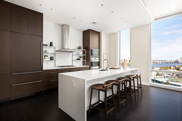 kitchen with a center island with sink, stainless steel appliances, dark hardwood / wood-style floors, sink, and a breakfast bar area