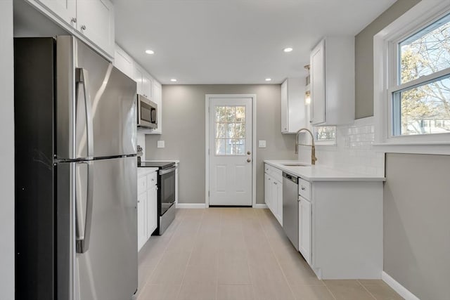 kitchen with sink, white cabinets, light tile patterned floors, decorative backsplash, and appliances with stainless steel finishes