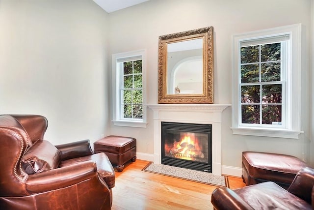 sitting room with a fireplace with flush hearth, baseboards, and wood finished floors