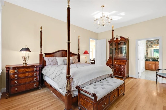 bedroom with ensuite bathroom, light wood-style flooring, and a chandelier