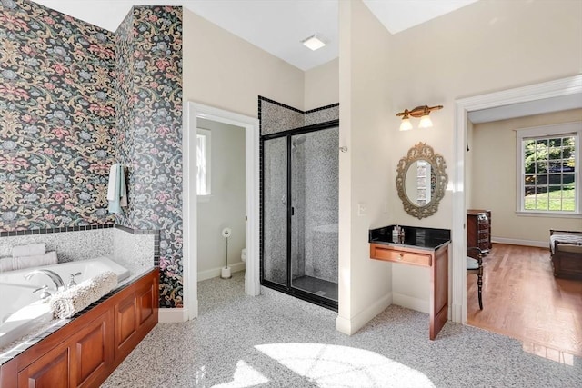bathroom with toilet, baseboards, a shower stall, and a garden tub