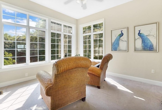 living area featuring baseboards, carpet flooring, and a ceiling fan