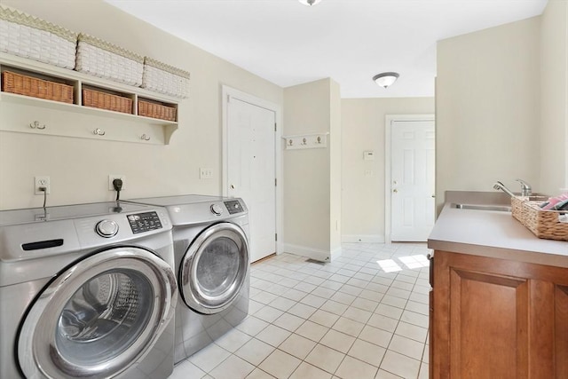 laundry area featuring laundry area, independent washer and dryer, a sink, light tile patterned floors, and baseboards