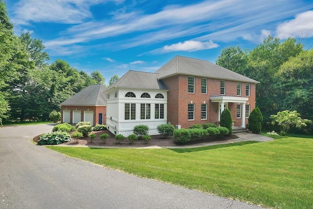 view of front of house featuring brick siding, a garage, aphalt driveway, and a front yard