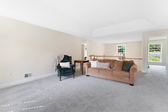 carpeted living area with visible vents, a raised ceiling, and baseboards