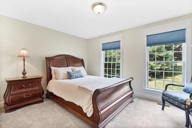 bedroom featuring baseboards, multiple windows, and light carpet