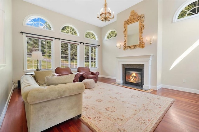 living area with baseboards, a fireplace with flush hearth, dark wood-style flooring, and a healthy amount of sunlight