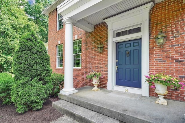entrance to property featuring brick siding and covered porch