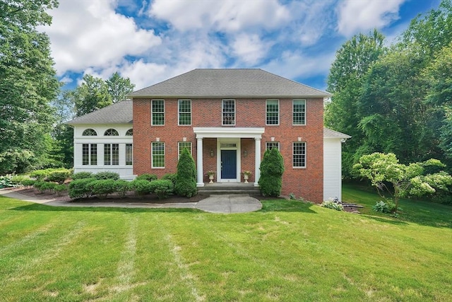 back of property featuring brick siding and a lawn
