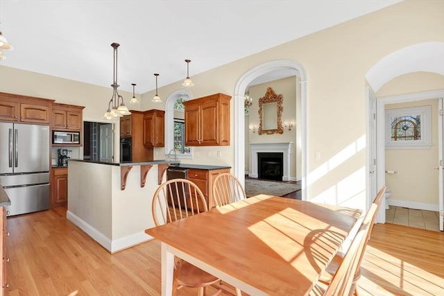 interior space with stainless steel appliances, arched walkways, light wood-type flooring, and a fireplace