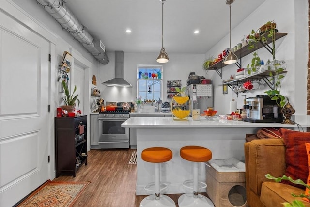 103-105 Broadway, Chelsea, MA 02150 - kitchen with wall chimney range hood, stainless steel gas stove, light countertops, wood finished floors, and fridge