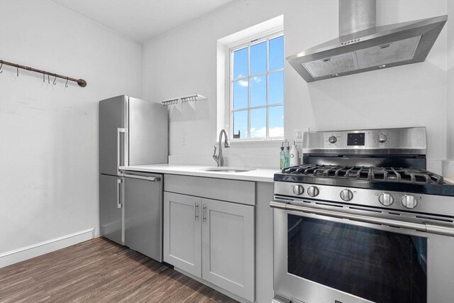103-105 Broadway, Chelsea, MA 02150 - kitchen featuring appliances with stainless steel finishes, wall chimney range hood, a sink, wood finished floors, and light countertops