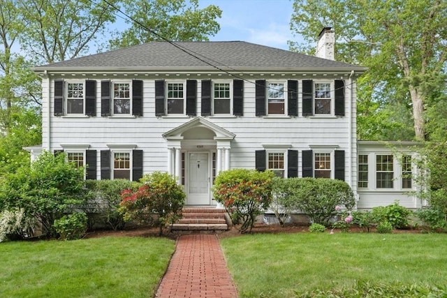 77 Meriam St, Lexington, MA 02420 - georgian-style home featuring a chimney, a front yard, and a shingled roof