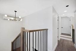 corridor with dark wood-type flooring and a chandelier