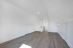 additional living space featuring dark wood-type flooring and vaulted ceiling