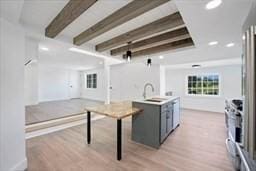 kitchen with gray cabinets, sink, beam ceiling, and light hardwood / wood-style floors