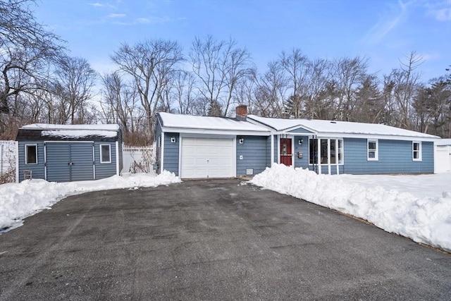 view of front of house featuring a garage, a chimney, and aphalt driveway