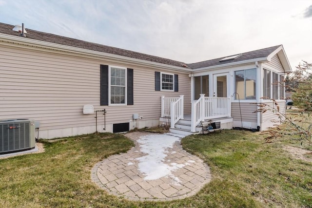 back of house with a sunroom, a lawn, and central AC