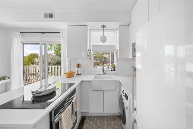kitchen featuring a sink, light countertops, freestanding refrigerator, washer / dryer, and visible vents