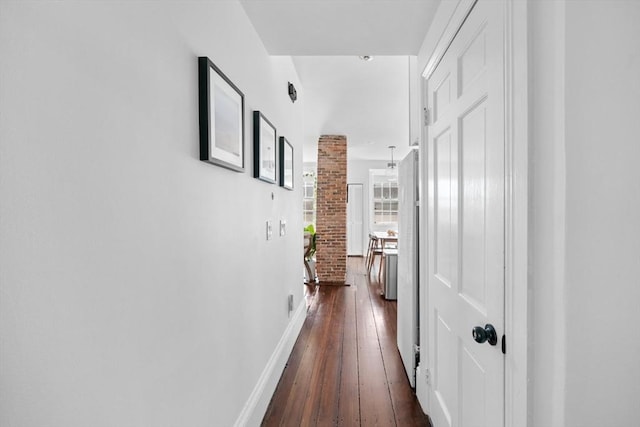 hall with dark wood-style flooring, baseboards, and decorative columns