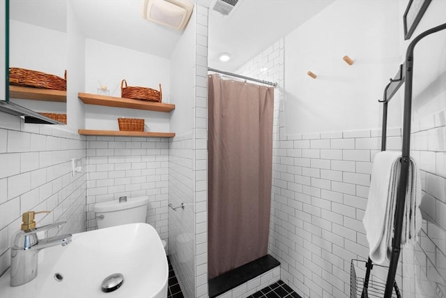 full bath featuring tile walls, a tile shower, a sink, and visible vents