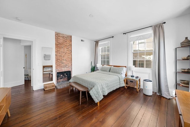 bedroom with visible vents, a fireplace, and hardwood / wood-style floors