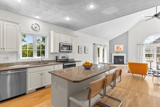 8 Mill River Ln, Rowley, MA 01969 - kitchen with appliances with stainless steel finishes, a kitchen island, dark stone counters, light wood-style flooring, and lofted ceiling