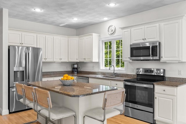 8 Mill River Ln, Rowley, MA 01969 - kitchen featuring appliances with stainless steel finishes, white cabinets, a kitchen bar, light wood-type flooring, and recessed lighting