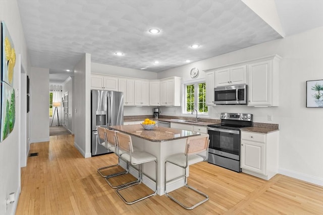 8 Mill River Ln, Rowley, MA 01969 - kitchen with stainless steel appliances, a kitchen breakfast bar, white cabinets, light wood-style floors, and recessed lighting