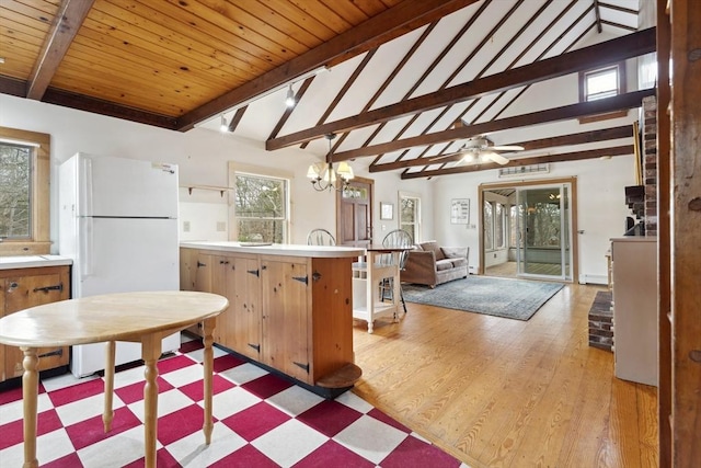 kitchen with light countertops, lofted ceiling with beams, light wood-style floors, freestanding refrigerator, and wood ceiling