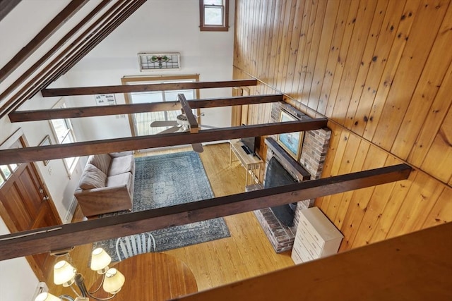 stairs with wood walls, vaulted ceiling, a notable chandelier, and wood finished floors