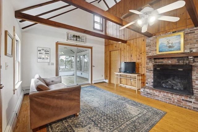 living area featuring a wealth of natural light, beamed ceiling, baseboard heating, and wood finished floors