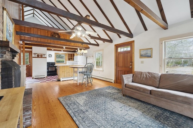 living area with a baseboard heating unit, a fireplace, beamed ceiling, and light wood finished floors