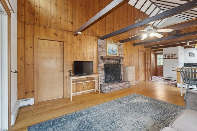 living area with ceiling fan, wooden walls, a fireplace, wood finished floors, and beam ceiling