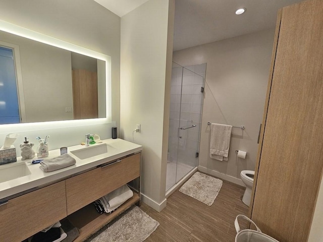 bathroom with hardwood / wood-style floors, toilet, walk in shower, and vanity